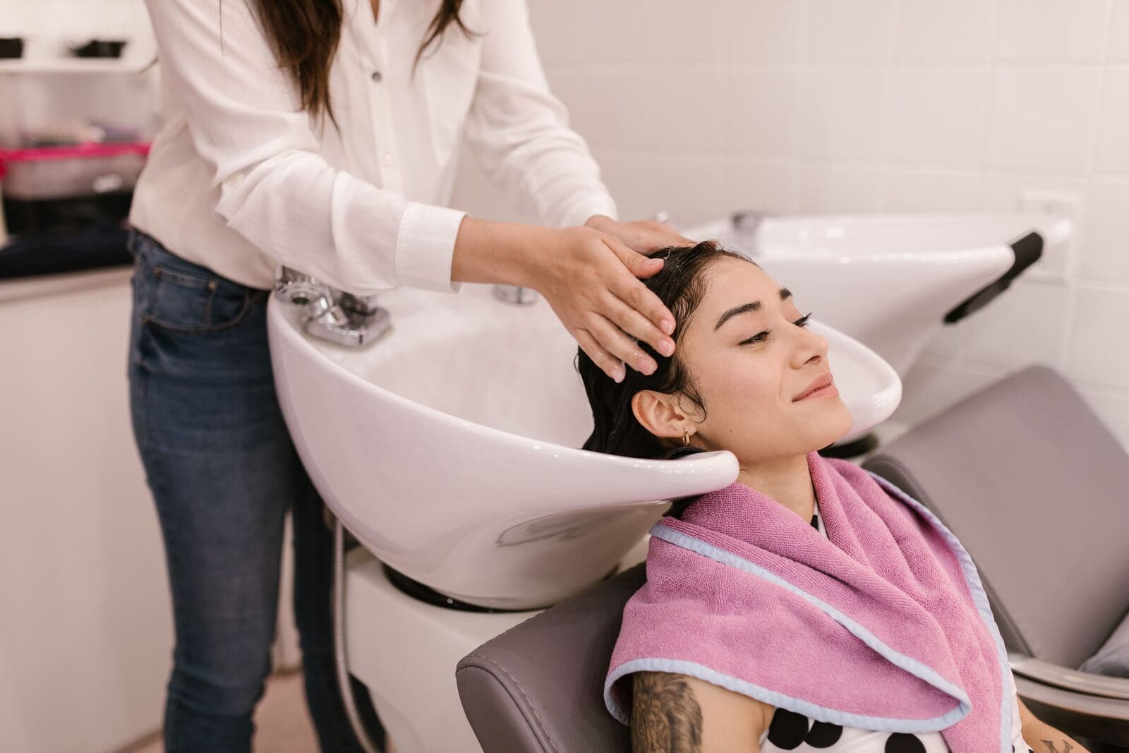A stylist washing a client's hair at the basin in a salon